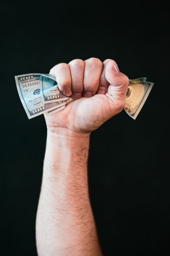 Close-up of a fist holding US dollars on a black background symbolizing financial strength.